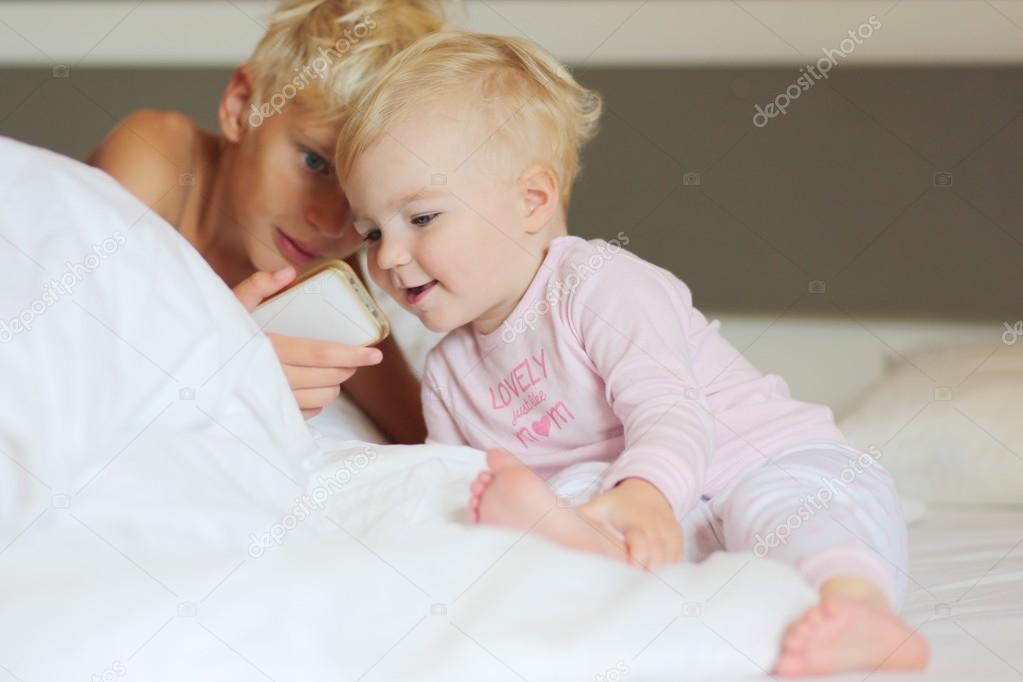 Boy with little baby sister laying in parents bed
