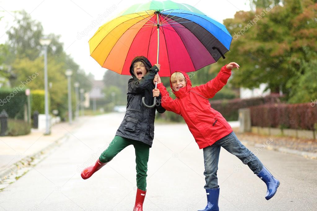 Twin brothers jumping under colorful umbrella