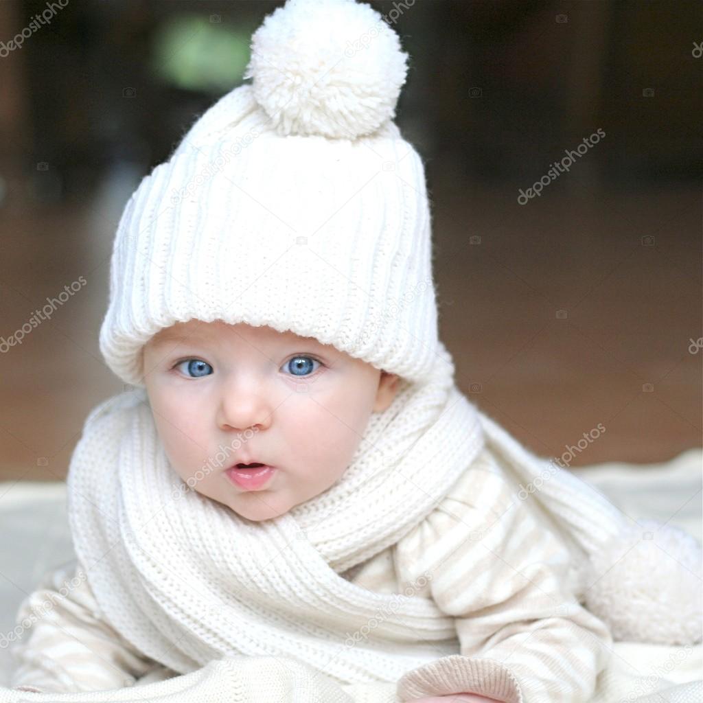 Baby in white knitted hat and scarf