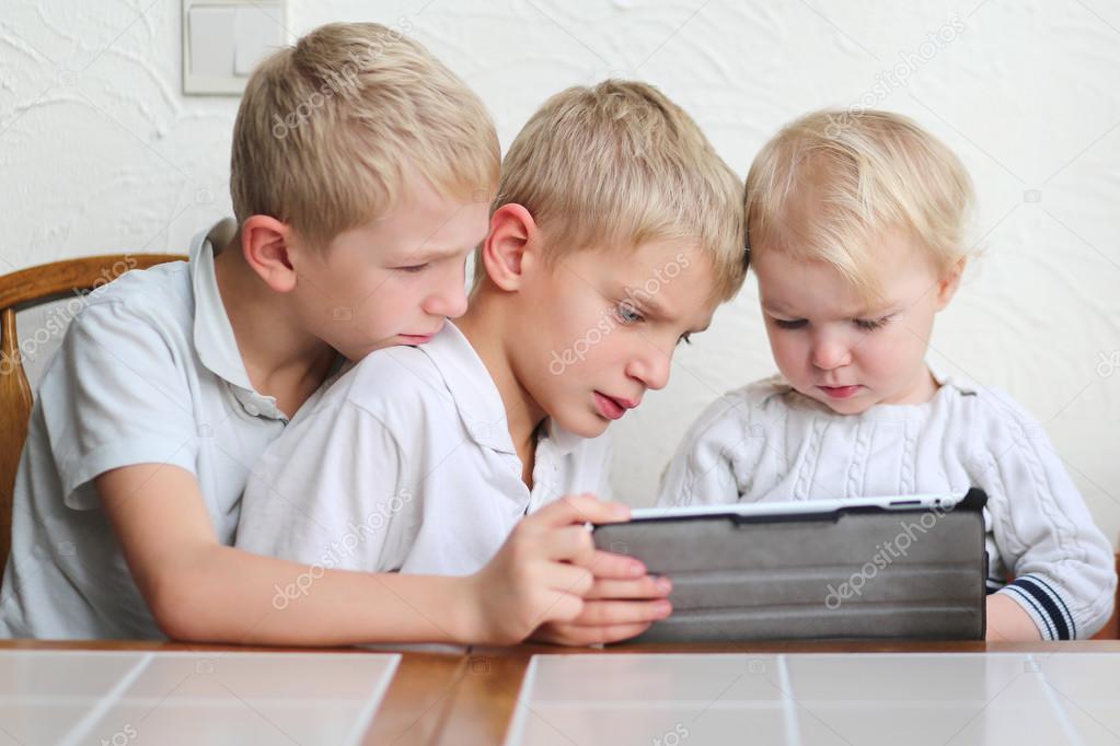 Brothers with sister playing on a tablet