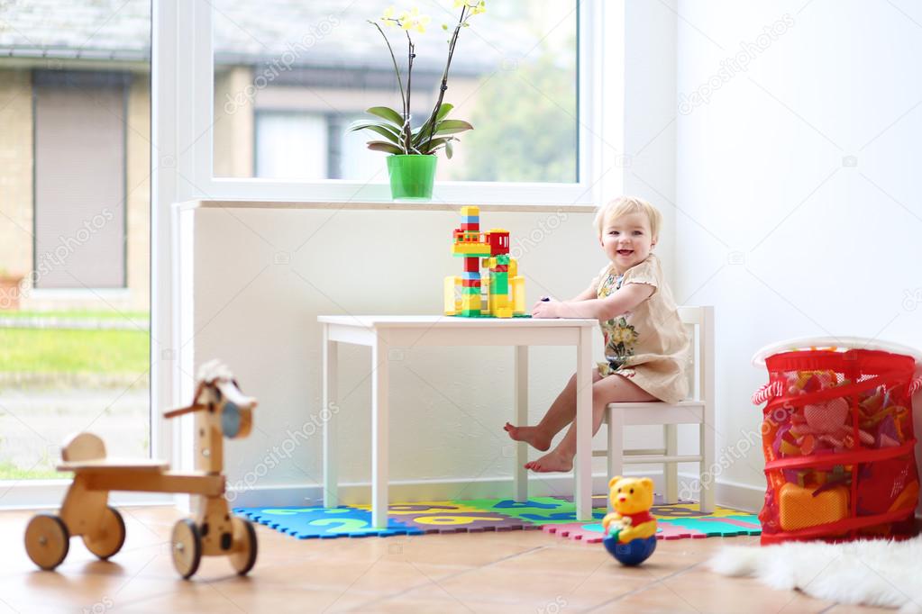 Girl building house from plastic blocks