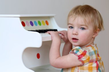 Kız piyano oyuncak üzerinde oynamak için öğrenme