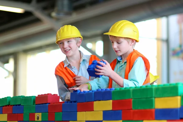 Brothers building a house with big plastic construction bricks — Stock Photo, Image