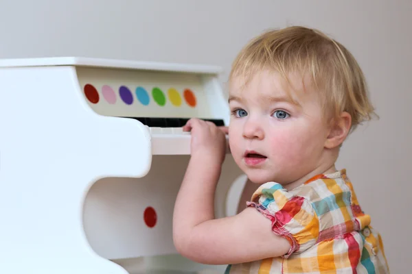 Niña aprendiendo a tocar en el juguete del piano — Foto de Stock