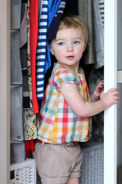 Toddler girl playing hide and seek in mother's wardrobe — Stock Photo, Image