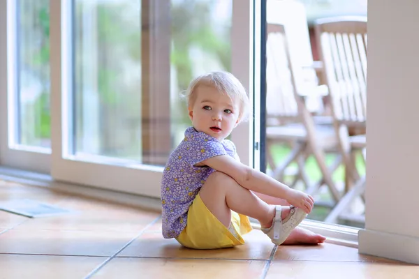 Flicka att sätta på sin sko som sitter på golvet — Stockfoto