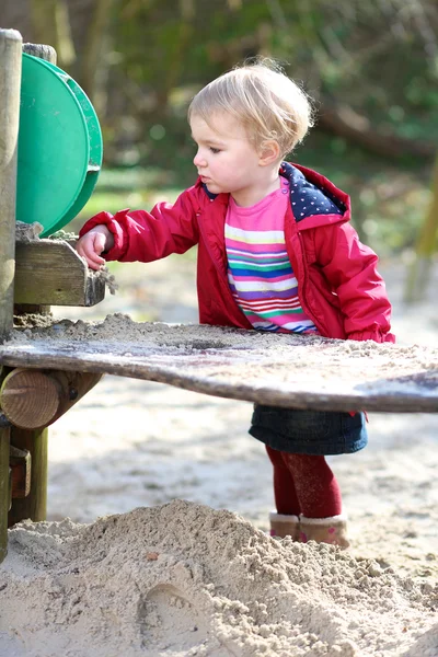 Девушка играет с песком на открытой площадке — стоковое фото