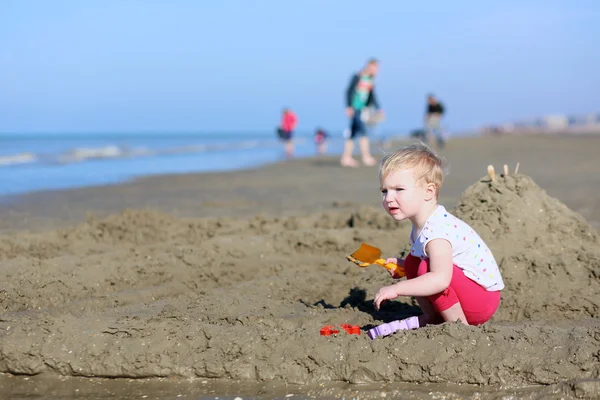 Chica jugando con juguetes de plástico en una orilla del mar —  Fotos de Stock