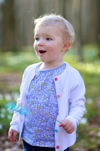 Tjej med blont lockigt hår spelar i skogen — Stockfoto