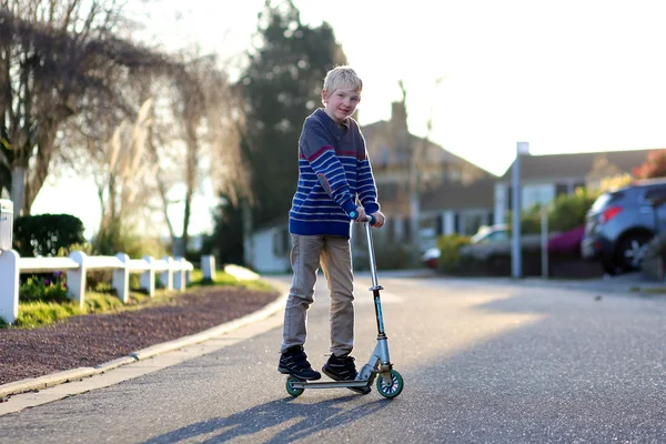 Çocuk sokakta oynarken scooter ile sürüş — Stok fotoğraf