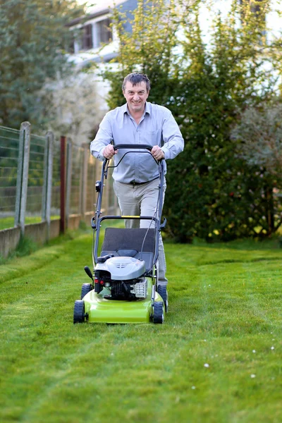 Man mowing the lawn in the backyard of his house — Stock Photo, Image