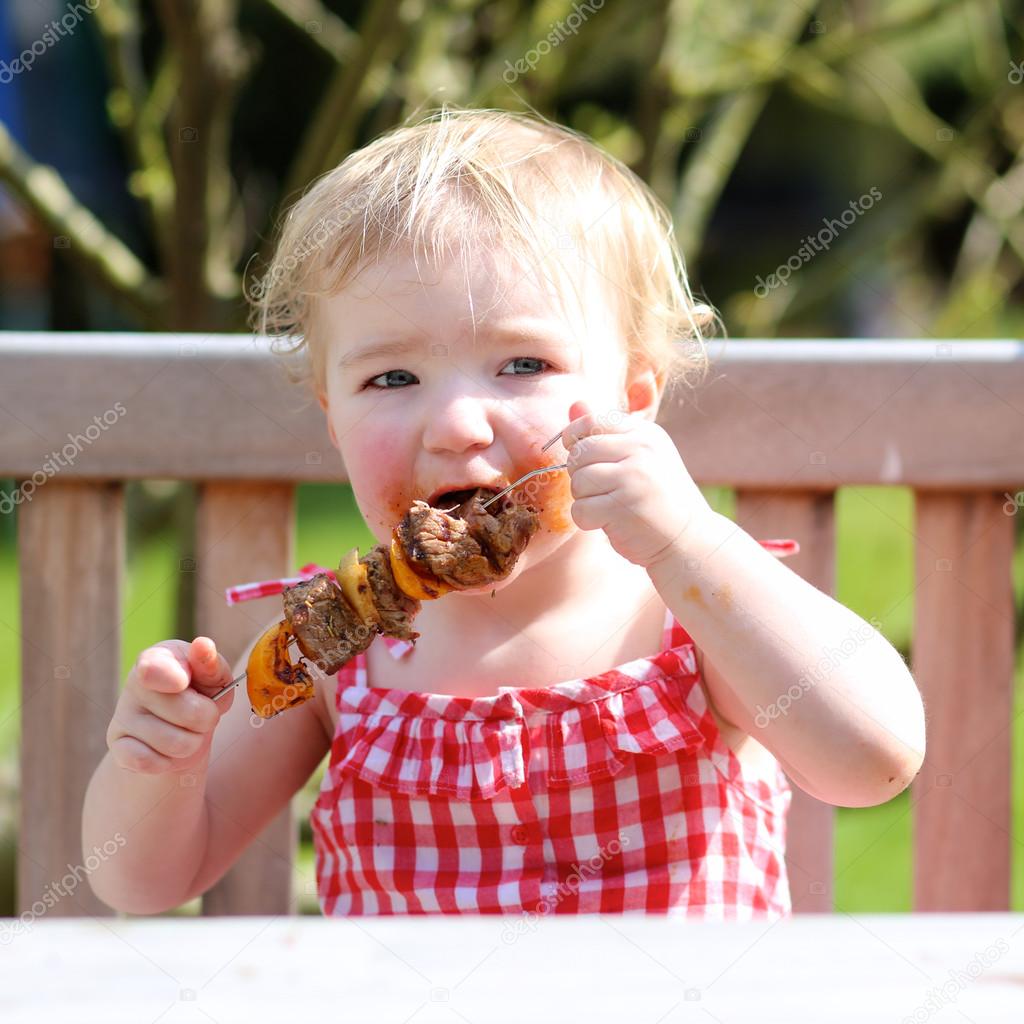 baby girl eating meat Funny child eating meat — Stock Photo © CroMary #43659189