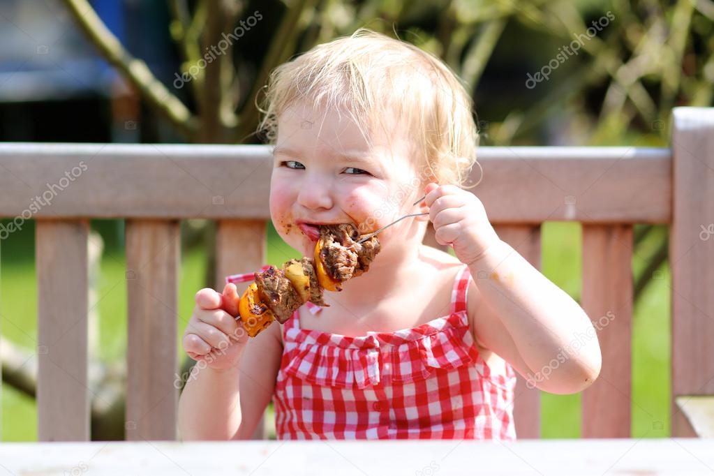 Girl eating meat made on barbeque