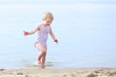 Benekli mayo kumsalda oynarken mutlu küçük kız
