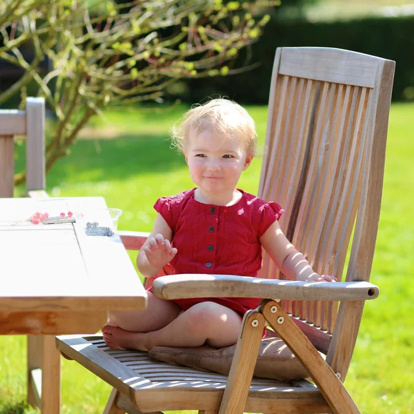 Feliz niña jugando en el jardín sentado en la mesa de picnic de madera — Foto de Stock