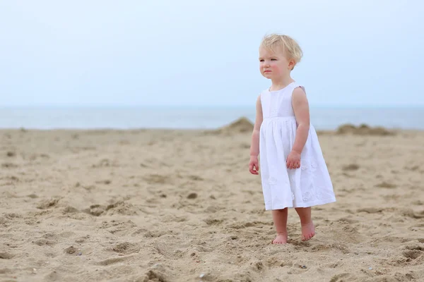 Portrait of beautiful toddler girl in white dress walking on the beach — Stock Photo, Image