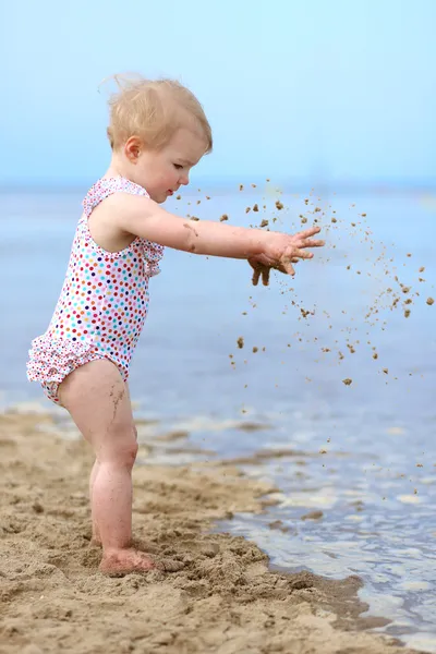 Niña feliz en traje de baño irregular jugando en la playa de arena —  Fotos de Stock