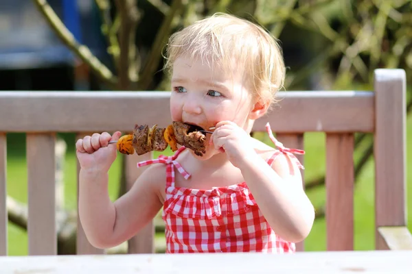 Menina feliz da criança comendo carne grelhada ao ar livre — Fotografia de Stock