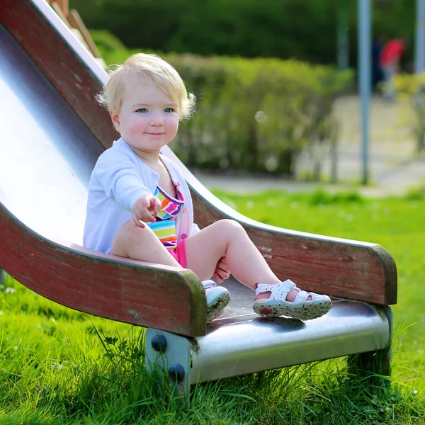 Ładny dziewczyna relaksujący na plac zabaw, siedząc na slajdzie — Zdjęcie stockowe