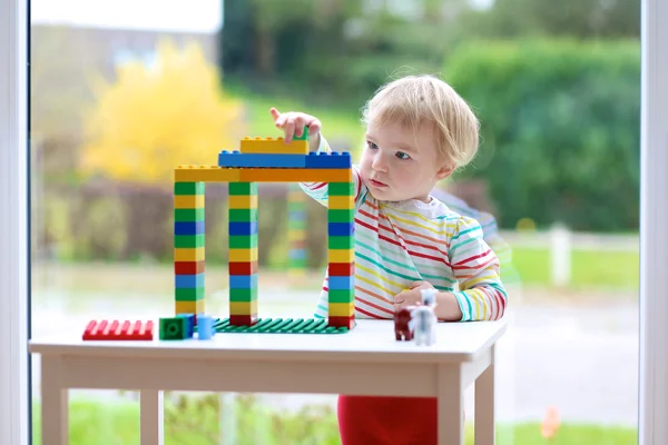 Fröhliche Kleinkind Mädchen spielt mit bunten Blöcken drinnen — Stockfoto