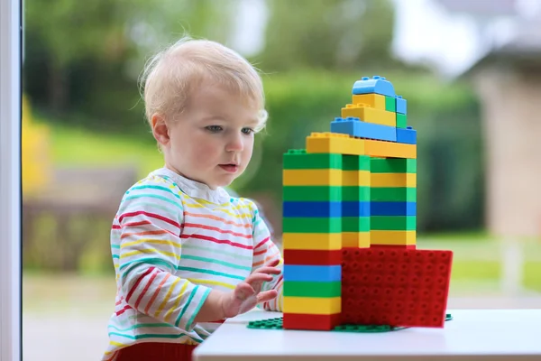 Fröhliche Kleinkind Mädchen spielt mit bunten Blöcken drinnen — Stockfoto