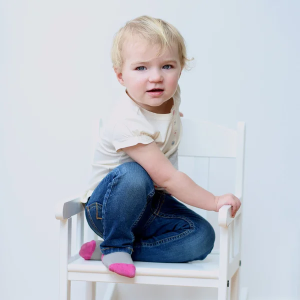 Portret van gelukkig kindje in casual kleding poseren binnenshuis op een witte schommelstoel — Stockfoto