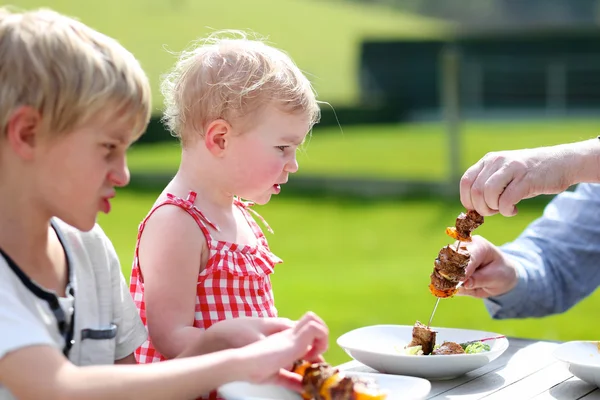 Vader zetten vlees voor kinderen, schattige peuter meisje en grappige tiener jongen. — Stockfoto