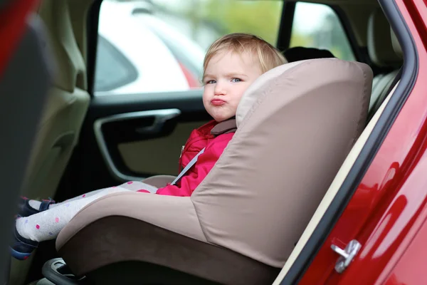 Girl sitting in a child seat in car — Stock Photo, Image