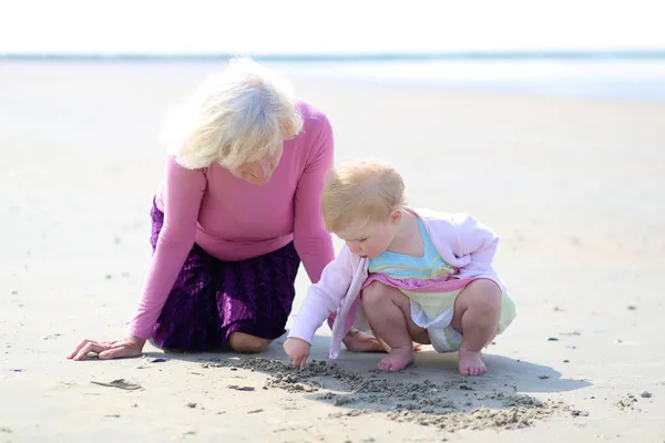 해변에서 그녀의 손녀와 함께 노는 행복 한 할머니 — 스톡 사진