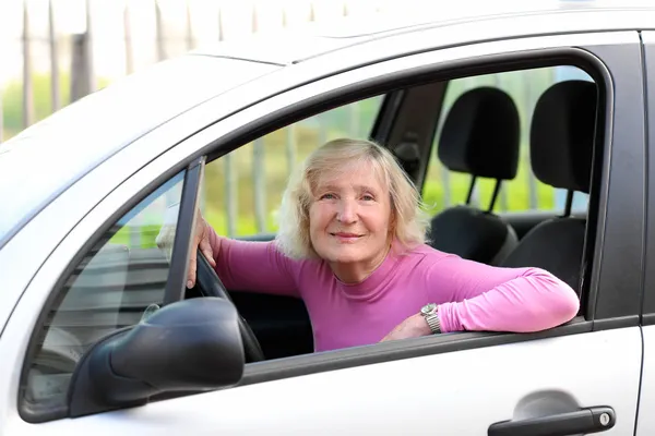 Счастливая пожилая женщина за рулем современного автомобиля — стоковое фото