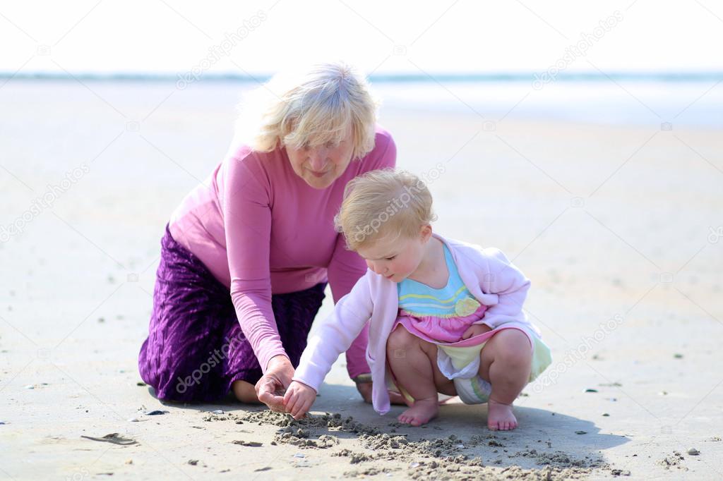 Happy grandmother playing with her granddaughter on the beach