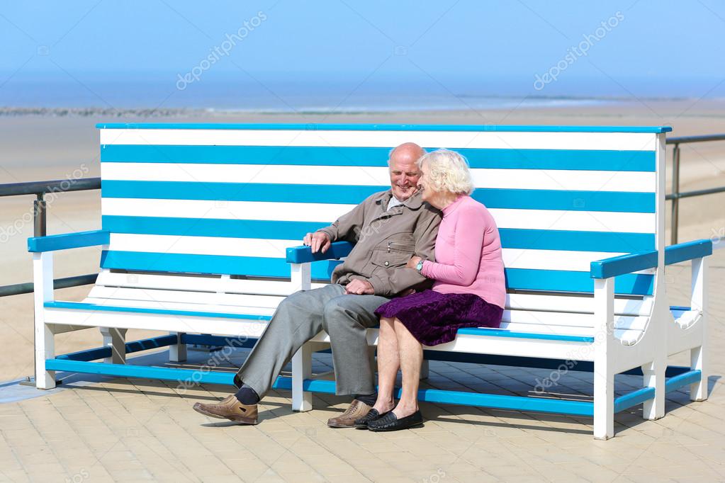 Happy senior couple relaxing on the promenade sitting on the bench