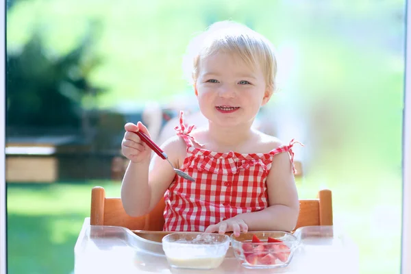 Menina comendo mingau com morangos — Fotografia de Stock