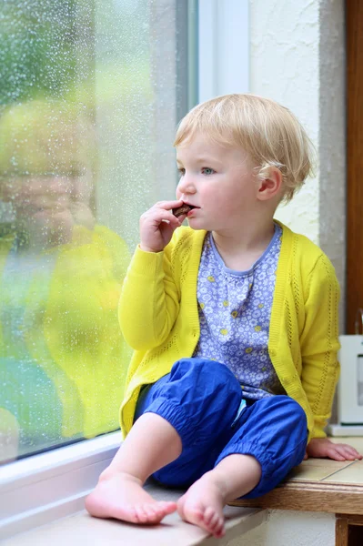 Menina comendo chocolate em um dia chuvoso — Fotografia de Stock