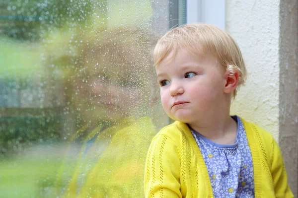 Lilla barnet tittar genom fönstret — Stockfoto