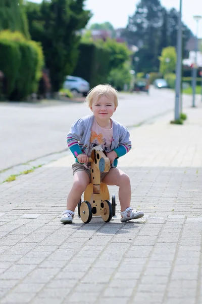 Klein meisje spelen op de straat haar push fiets rijden — Stockfoto