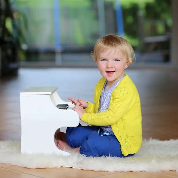 Niña tocando el piano de juguete en interiores — Foto de Stock