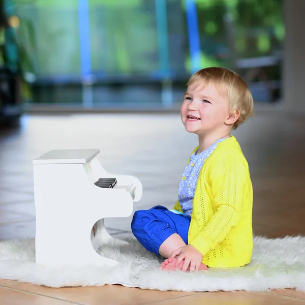 Klein meisje spelen speelgoedpiano binnenshuis — Stockfoto