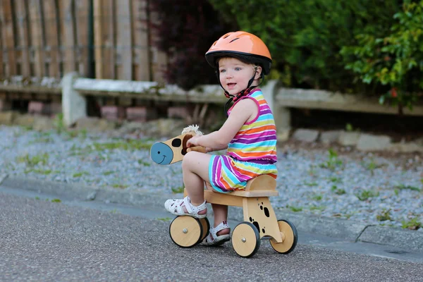 Happy little child in safety helmet riding wooden tricycle — Stock Photo, Image