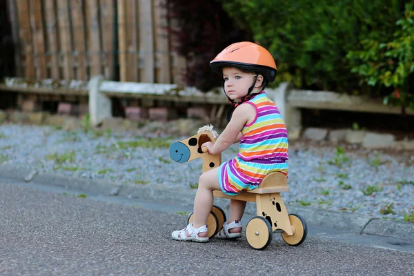 Criança feliz no capacete de segurança equitação triciclo de madeira — Fotografia de Stock