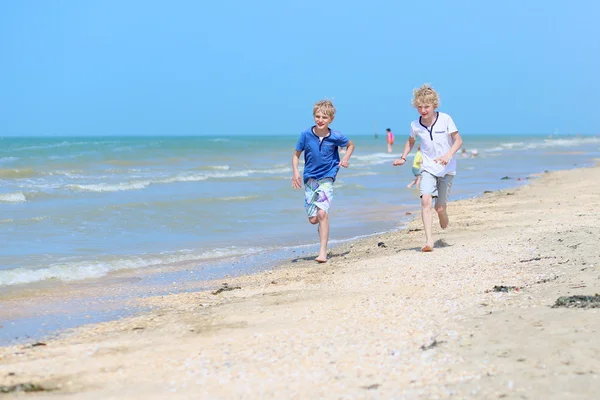 Active school boys running on beautiful beach Stock Image