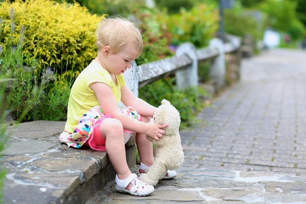 Cute little girl playing with teddy bear on the street — Stock Photo, Image