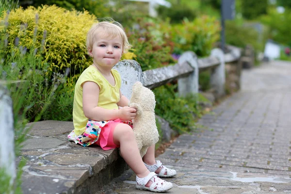 Niedliches kleines Mädchen spielt mit Teddybär auf der Straße — Stockfoto