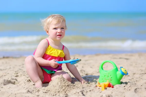 Menina feliz construindo castelos de areia na praia — Fotografia de Stock