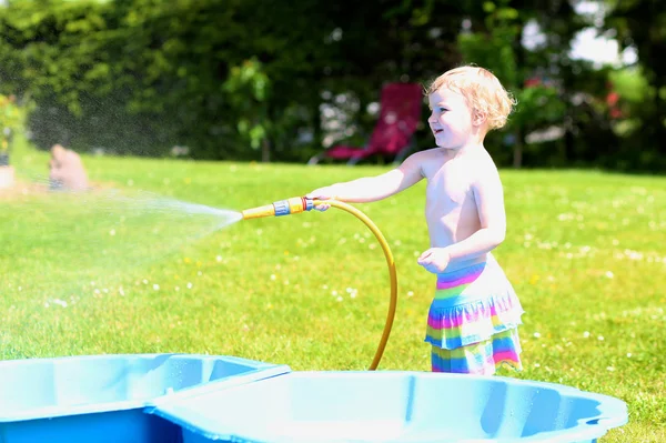 Gelukkig meisje spelen met waterslang in de tuin — Stockfoto