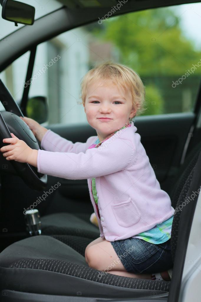 Happy little child sitting inside of the car holding steering wheel ... Happy little child sitting inside of the car holding steering wheel ...