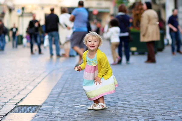 Glad liten flicka äter glass i centrera av staden — Stockfoto