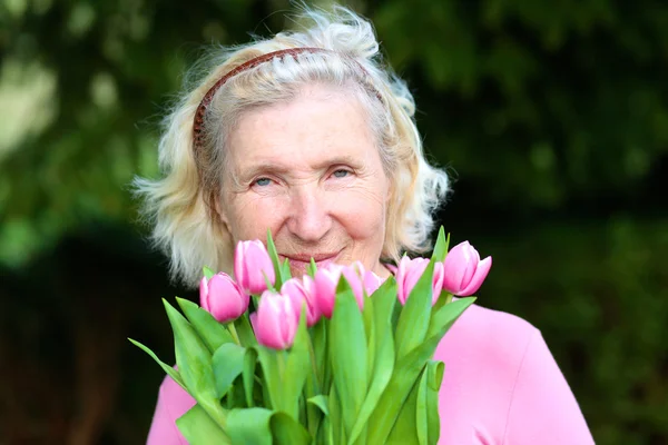 Retrato de mujer mayor feliz con ramo de hermosos tulipanes rosados — Foto de Stock