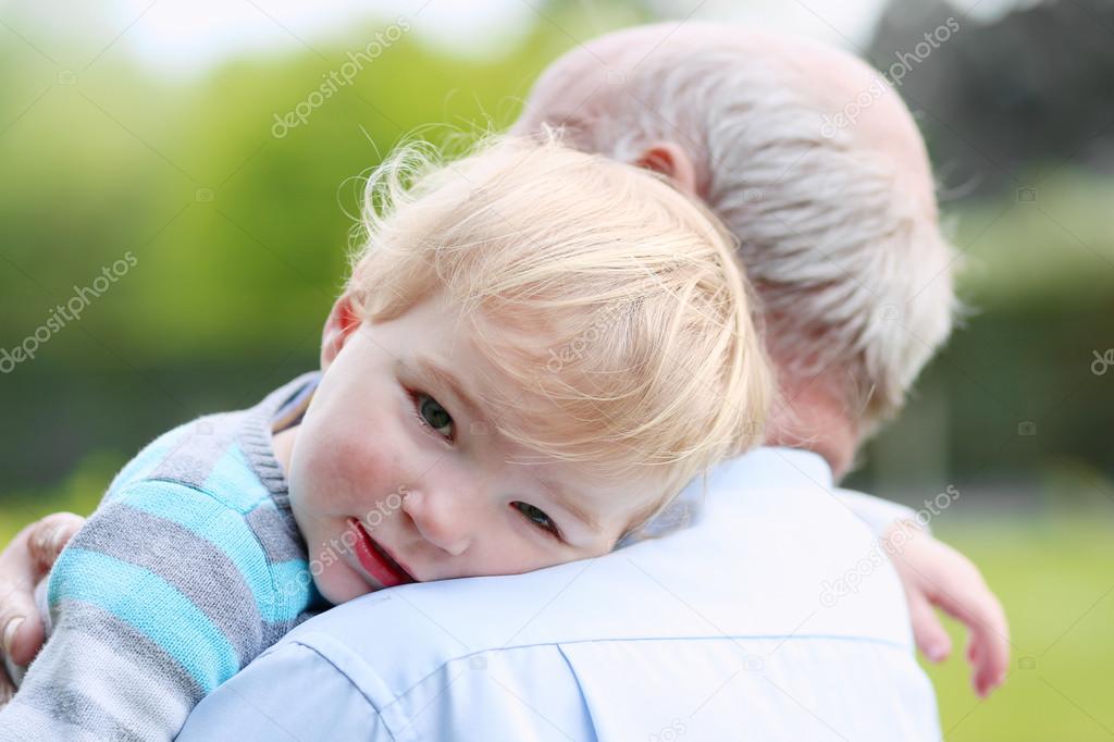 Cute little child comforting on the shoulder of grandfather