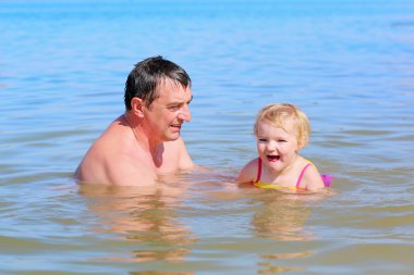 Küçük kızı sıcak güneşli bir günde gölde yüzme ile etkin baba